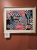 Framed abstract painting with blue flowers and checkered pattern on red background