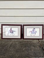 Photo showing both watercolor paintings side by side outdoors against wall.