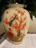 Front and side view of a porcelain vase with intricate bird and floral design on cream glaze.