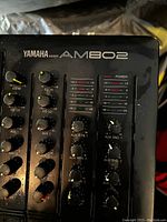 Close-up image showing Yamaha AM802 label, EQ controls, auxiliary return and send knobs, and power indicator.