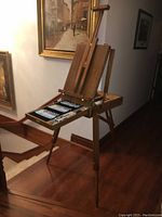 Tripod easel assembled and front drawer open showing paint tubes