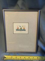 Framed color etching in silver-tone frame with a measuring tape indicating size.