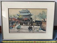 Frontal view of the framed watercolor painting showing the Korean village scene with people and traditional architecture under glass and matte.