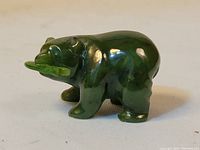Side view of the dark green jade bear figurine showing the bear's shape and smooth finish.