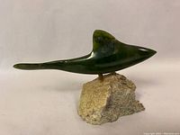 Full side view of the green BC jade fish sculpture on stone base showing the shape and color variation of the jade.
