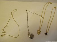 Four necklaces laid out on a white surface, showing overall condition and style.