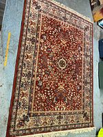 Photograph of the full carpet spread out on the floor showing the central floral medallion and border detailing.