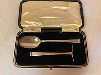 Set of child's sterling silver spoon and plate pusher in open fitted black display case with satin and velvet lining