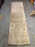 Full view of the thick wool runner carpet showing its length and overall design on a concrete floor.