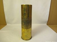 Full view of the brass artillery shell showing the upper part smooth and the middle section engraved.