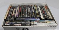 Box full of assorted DVD cases standing upright, showing spines and titles like Boys in Prison, Gunrunner, John Wayne, etc.