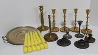 Wide view of all candlesticks, yellow taper candles in plastic packaging, and metal serving tray