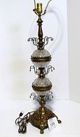 Full view of the lamp showing top harp, two crystal spheres, ornate brass base and power cord.