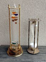 Galileo thermometer and sand hourglass timer displayed side by side with visible details.