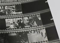Close-up view showing multiple black and white photographic proofs on film strips with urban scenes and people.