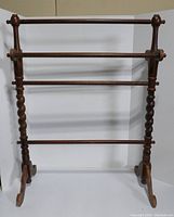 Front view of wooden quilt rack with three bars and twisted turned vertical posts.