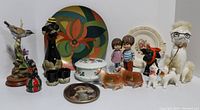 Full lot view showing all items including dog figurines, poodle figurine, cow salt and pepper shakers, covered dish, decorative plates, and boy/girl figurines.