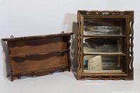 Two vintage wooden wall shelves placed side by side. One shelf has a mirror back and three compartments with decorative carved edges while the other is a simple wooden shelf with hooks beneath.