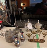 Shot showing entire assortment on table: vintage copper kettle, beaded bud vases, metal candle holders, lidded jars
