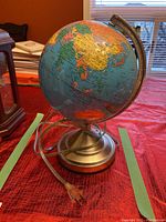Photo of the globe table lamp showing the globe and metal base with electrical cord and plug.