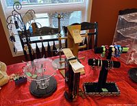 Wide view of six jewelry display stands on a red table cloth, showing varying designs, materials and heights, with jewelry visible on some stands (not included).