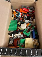 Box containing various loose LEGO bricks and pieces in multiple colors and shapes