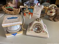 Photo showing the vintage rotary floral porcelain phone and porcelain dome nightlight in box on a table.