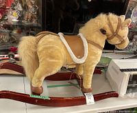 Side and angled view of the blonde plush rocking pony on wooden curved rockers showing saddle and reins.
