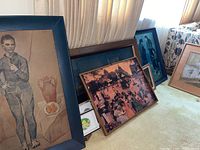 Multiple framed wall decorations leaning against wall on carpet