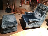 View showing chair and ottoman together in a room setting with tools and bags in background.