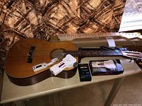 Photo of a Decca acoustic guitar on a table with multiple guitar tuners and accessories around it.