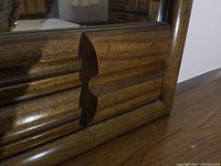 Close-up of corner wood detail showing carved design and wood grain texture.