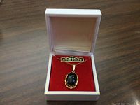 Pendant necklace displayed in white box on red velvet