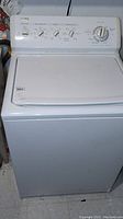 Full front view of white Kenmore Elite top load washer with closed lid and visible control panel.