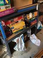 Metal rack with wood shelves holding various puzzle boxes and bags beneath, showing structure and condition.