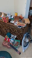 Lot arranged on wooden cabinet with plush bears, dog figurine, playing card sets, wooden cribbage board, small wooden boxes, guitar, and other items visible.