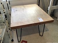 Full top and side view of wooden table showing stains and edge chip.