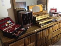 Wide shot showing four jewelry boxes, wooden desk organizer and assortment of small accessories spread across dresser