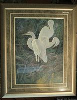 Framed print showcasing three white heron-like birds in a natural wooded setting, lots of green foliage and brown branches, gold and brown mat framing, rustic gold toned frame