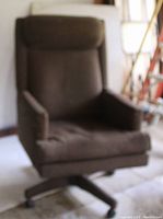 Photo of a brown cloth-covered executive swivel chair with high backrest and cushioned armrests on a five-wheel base