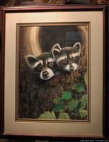 Framed print of two raccoons peeking from a tree hollow, showing detailed view of print and frame.