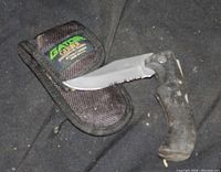 Photo of fixed blade knife with textured rubber handle and partially serrated edge next to its nylon carrying case with Gerber logo patch.