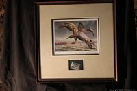 Framed art print showing flying ducks with an attached duck stamp below the artwork within matting.