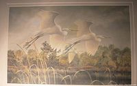 Limited edition print showing three white egrets flying over a wetland area, set against a softly colored natural landscape, matted.