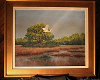 Frontal view of painting showing marsh landscape, flying egret and gold-tone frame