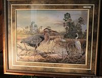 Framed limited edition print depicting herons in a wetland landscape, signed and titled 'Serenity'