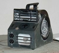 Front angled view of the squirrel cage fan showing handle, front grill, side intake with mesh, and control panel with switches.