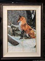 Framed acrylic painting showing a fox sitting in snow against a background of trees and rocks, with cream mat and dark wood/gold frame.