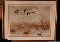 Full view of framed limited edition print showing ducks flying over a marshland with bare trees, matted and framed in gold.