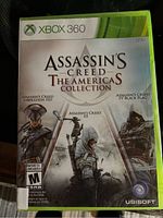 Front cover of sealed Assassin's Creed The Americas Collection game for Xbox 360 showing art from Liberation HD, Assassin's Creed III, and Black Flag.